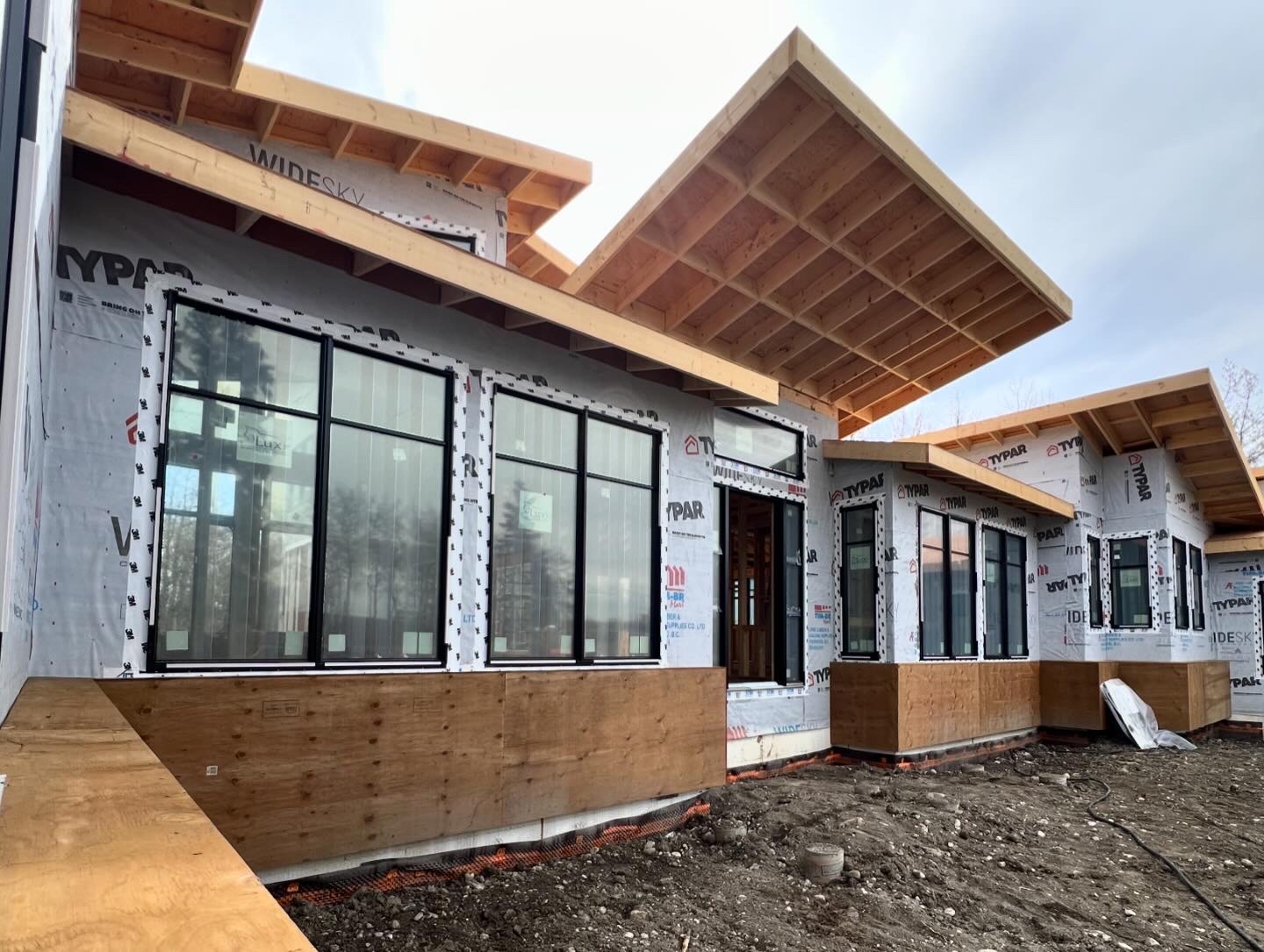 Cantilevered timber roof overhang above black window units